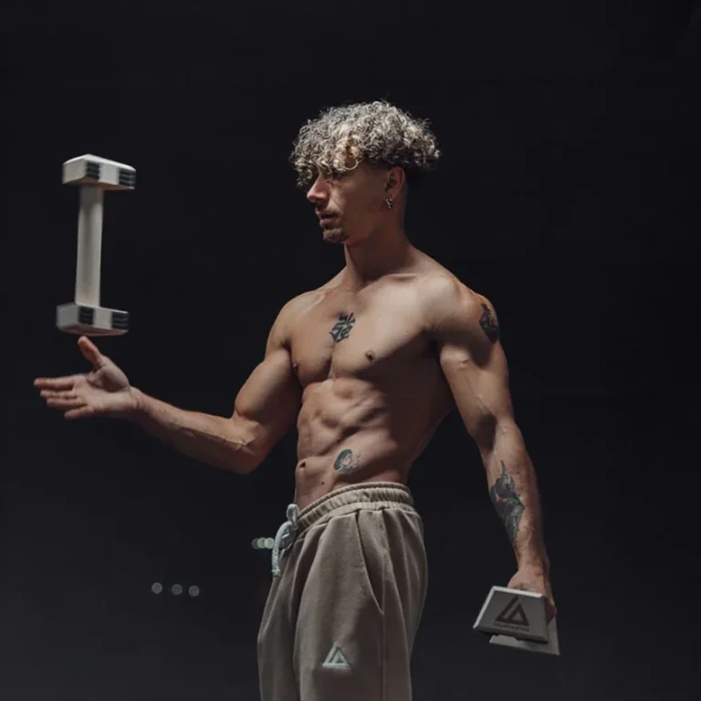 a shirtless man holds a dumbbell A shirtless man grips a dumbbell in low light, highlighting his dedication to weightlifting and physical fitness.